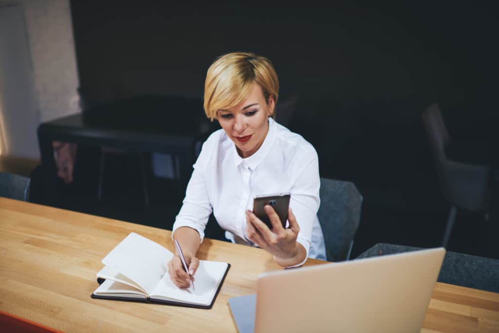 Positive secretary surfing internet on smartphone in office