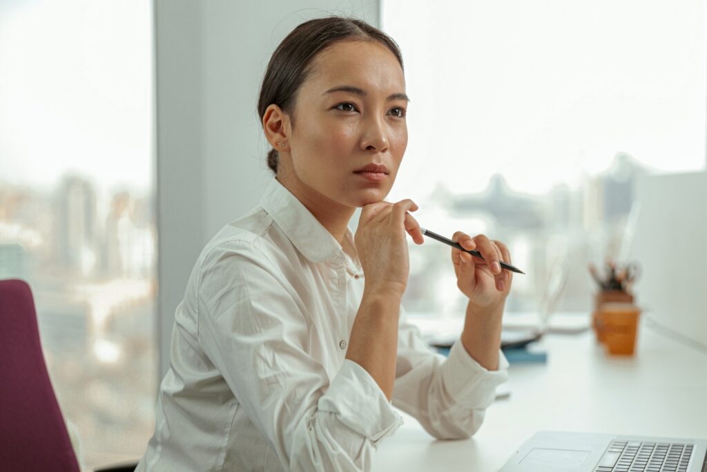 focused asian business woman sitting in office on her workplace and looks away, protect untrue crime, justice unfounded crime police, story, co workers, accused legal action, criminal charges, false report law firm, sexual assault, sexual harassment