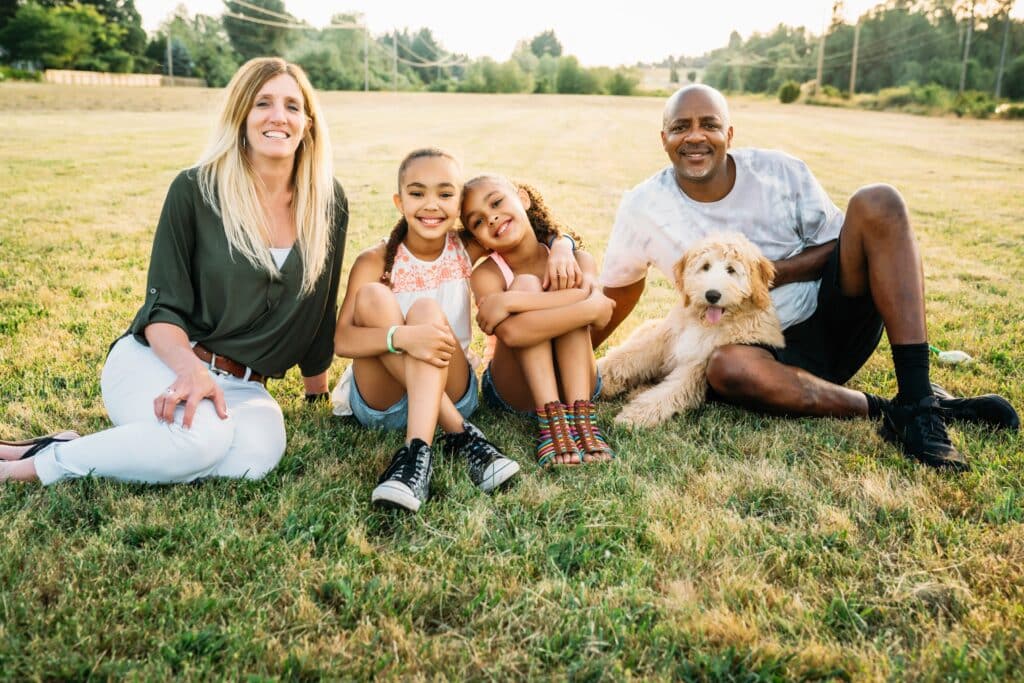 Portrait of mixed-race family in field with labradoodle puppy, such cases appropriate response, accused, lawyer, legal action, circumstances, protect, police, upper hand, unfounded crime, justice innocent, protect defending
