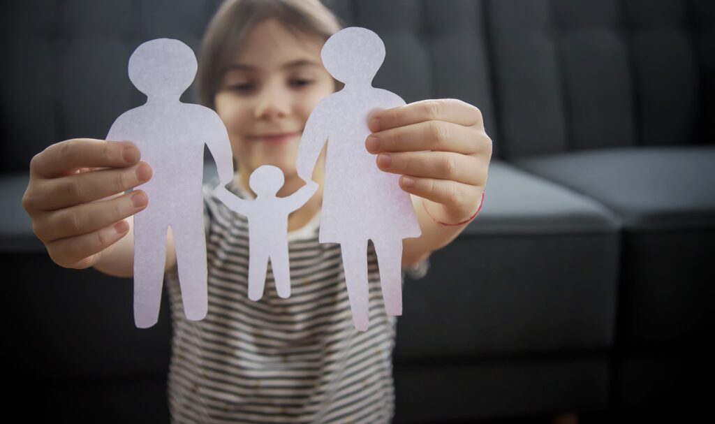 Child with a paper family in his hands.