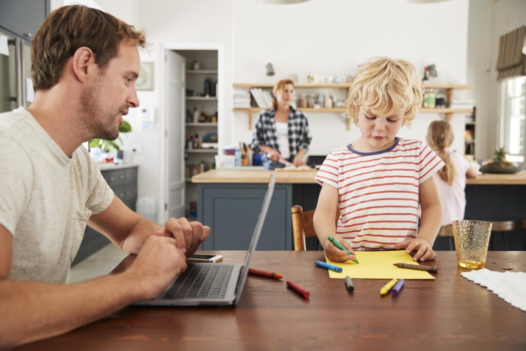 Busy family kitchen, dad and son working at table, close up