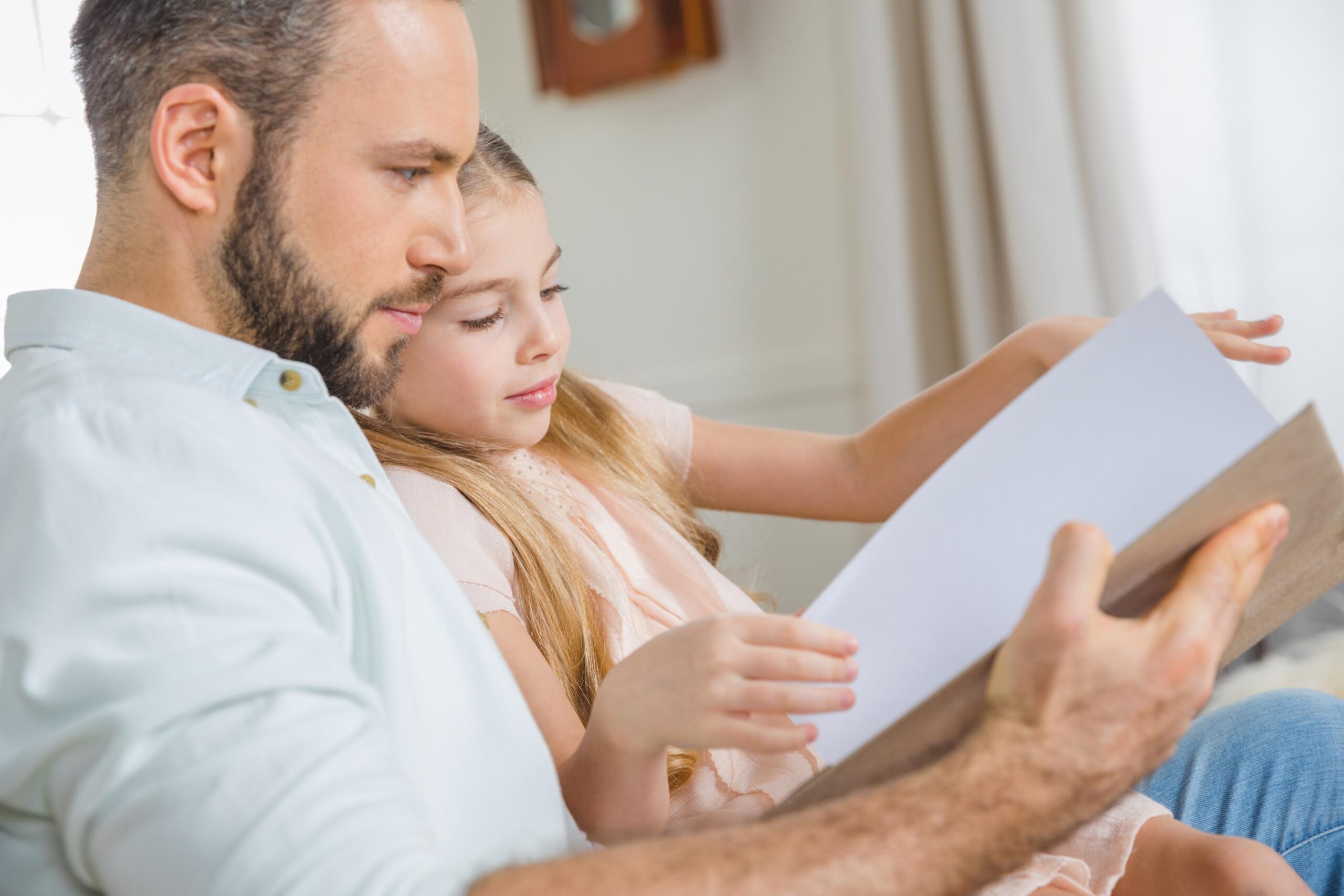 Portrait of pensive father and daughter reading book together