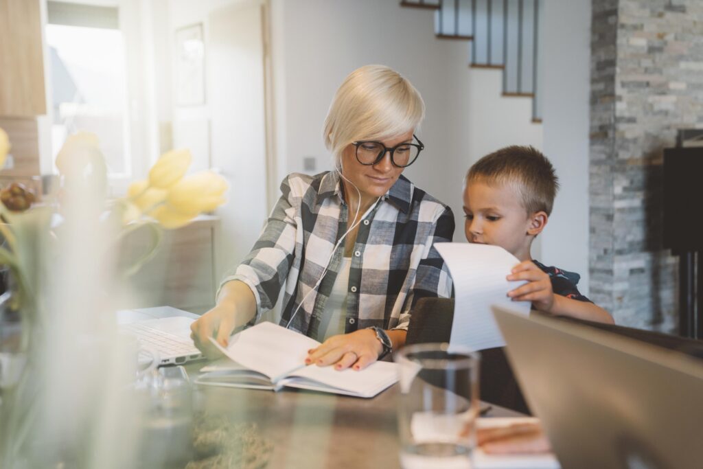 Mother helping his son with schoolwork, while trying to do some work from home herself
