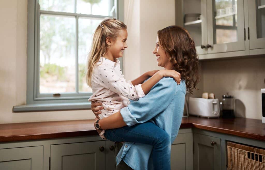 Happy Girl Embraces Smiling Woman Indoors
