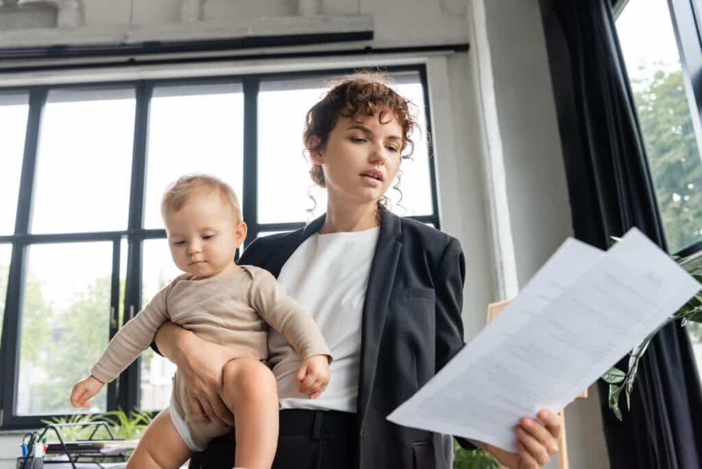 Working Woman Holding Her Baby While Reading Documents