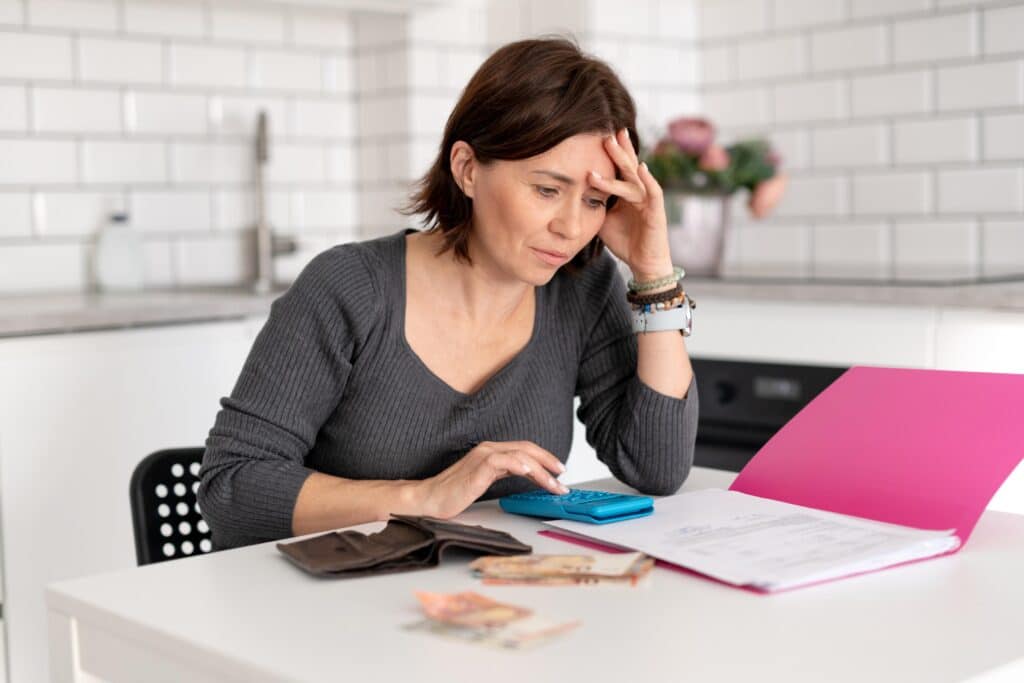 Woman with Head in Hand Calculates Finances at Home